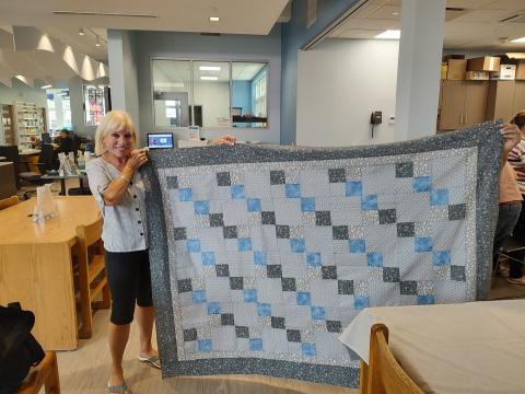 patron holding up a finished quilt