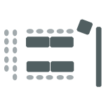 Tables facing each other with chairs on outside of tables, rows of chairs, podium, and a screen.