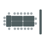 Five tables pushed together with chairs surrounding the tables and one screen.